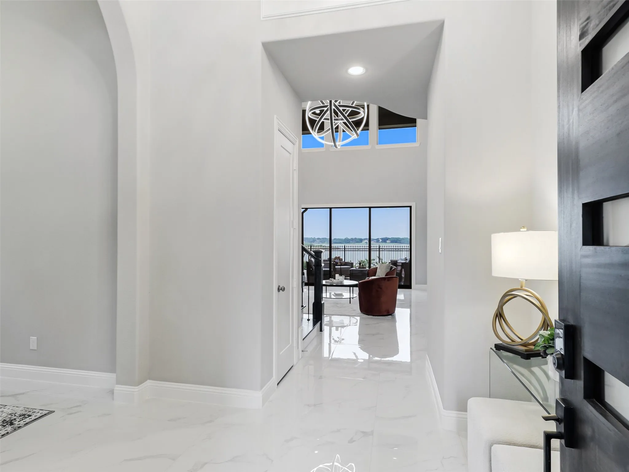 Bright entry featuring white tile flooring, vaulted ceilings, and an arched hallway