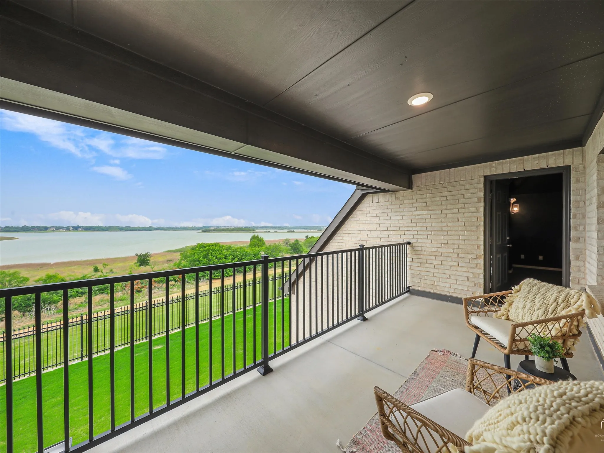 Covered balcony featuring a concrete floor and black metal railing