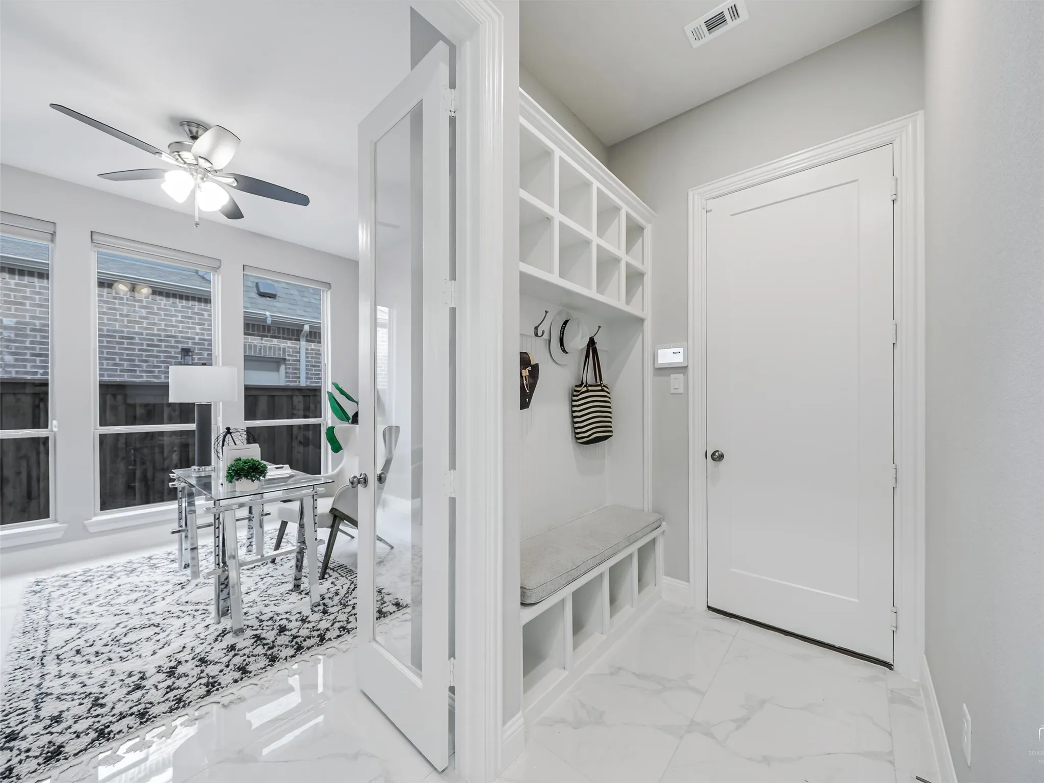 Entryway features built-in storage with cubbies and coat hooks, complemented by polished tile flooring