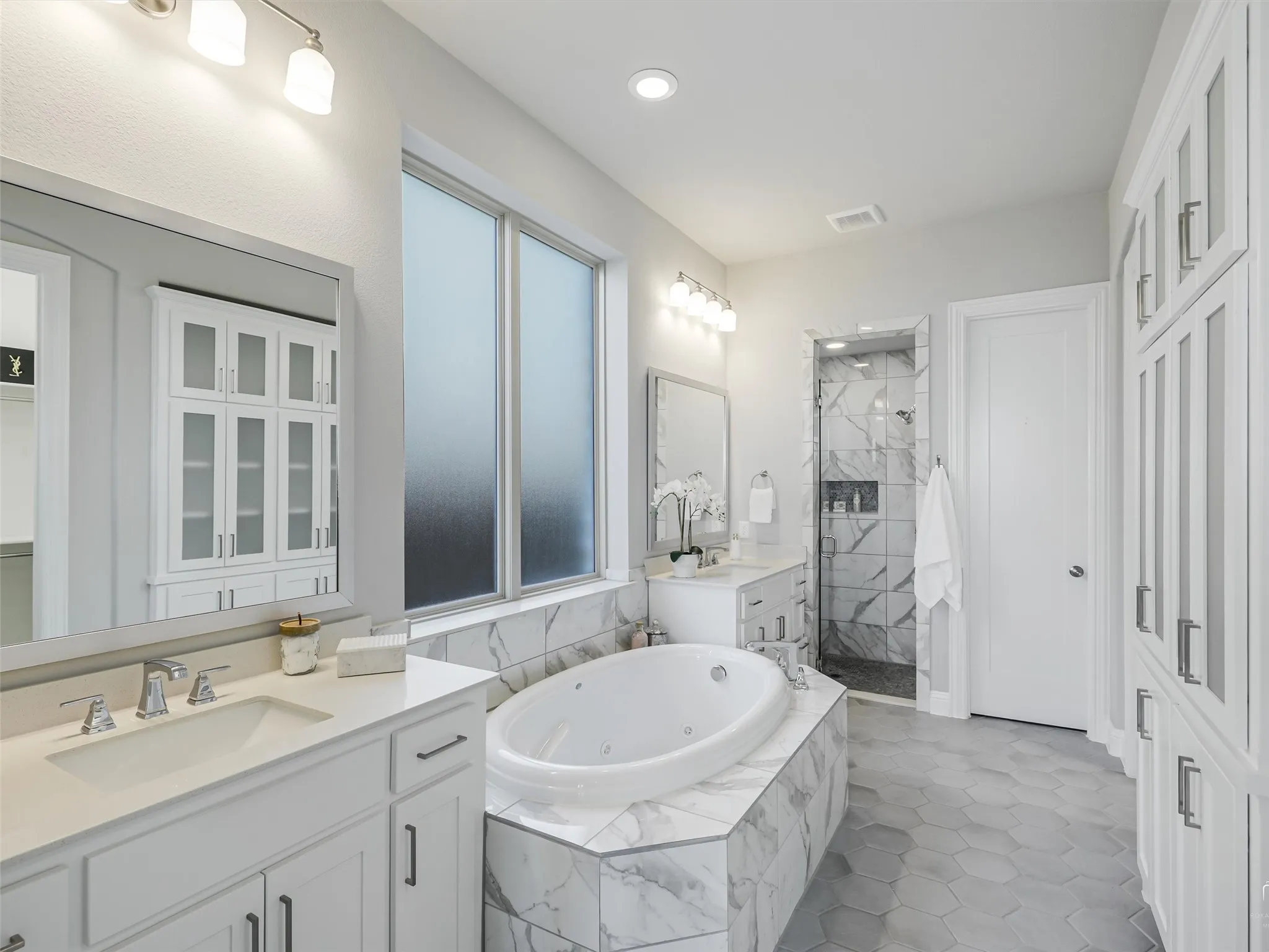 White-finished cabinetry and hexagon tile flooring define this bright bathroom