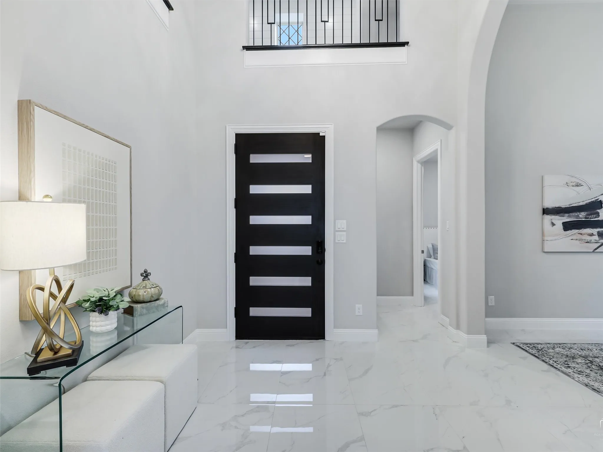 Foyer with a double-height ceiling, large format white tile flooring, and a contemporary entry door with horizontal lites