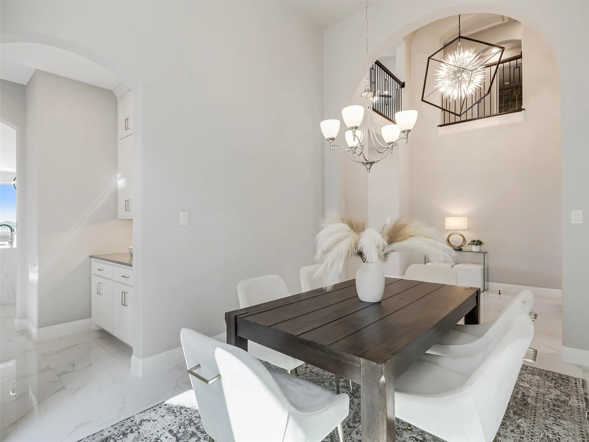 Dining area featuring an elegant chandelier, high ceilings, arched doorways, tile flooring, and a butler's pantry with white cabinetry