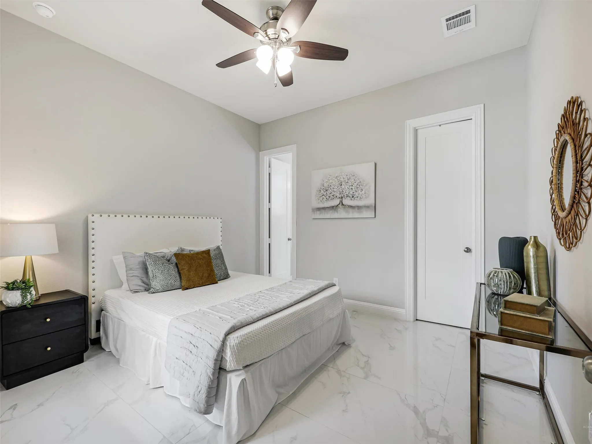 Bedroom featuring polished tile flooring, a ceiling fan with integrated lighting, and a white paneled door