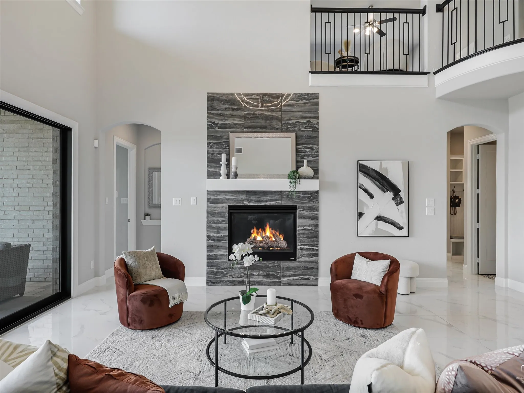 Two-story living area featuring a fireplace with stacked stone surround, white mantel, and a mounted mirror