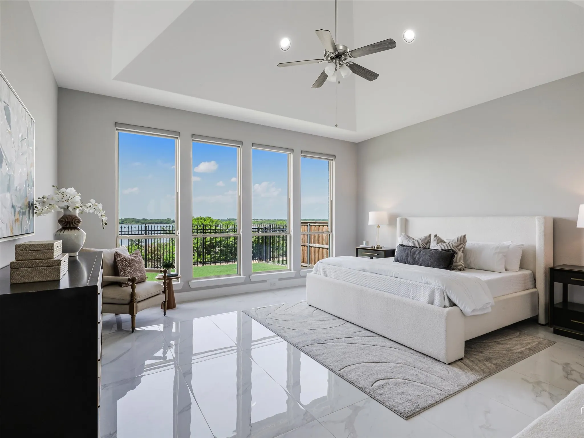 Spacious room featuring a vaulted ceiling with a ceiling fan, a wall of three large windows, and reflective tile flooring