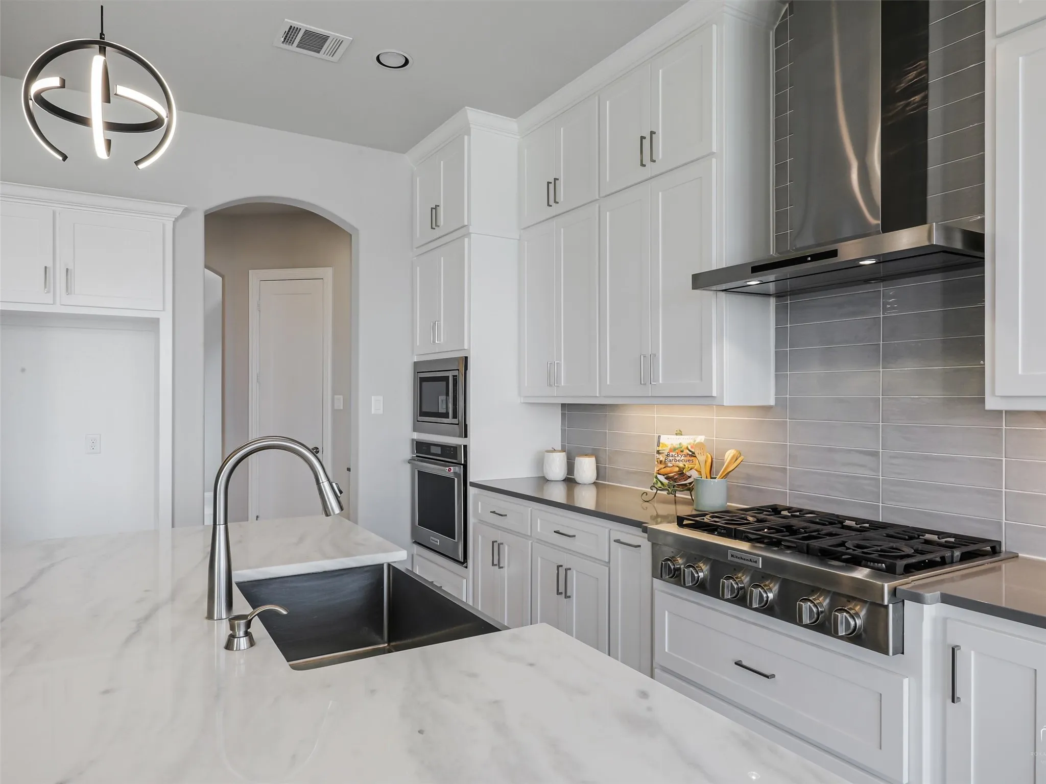 Gourmet kitchen featuring a large kitchen island with a stainless steel sink and gooseneck faucet
