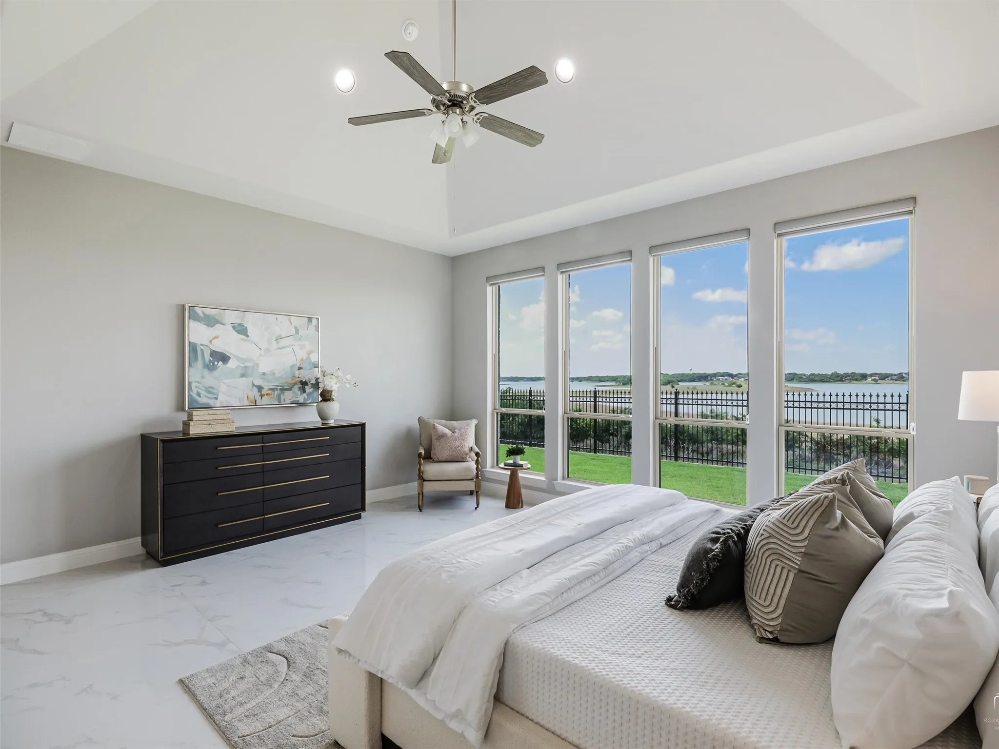 Spacious bedroom featuring multiple large windows, a tray ceiling, recessed lighting, a ceiling fan, and tile flooring