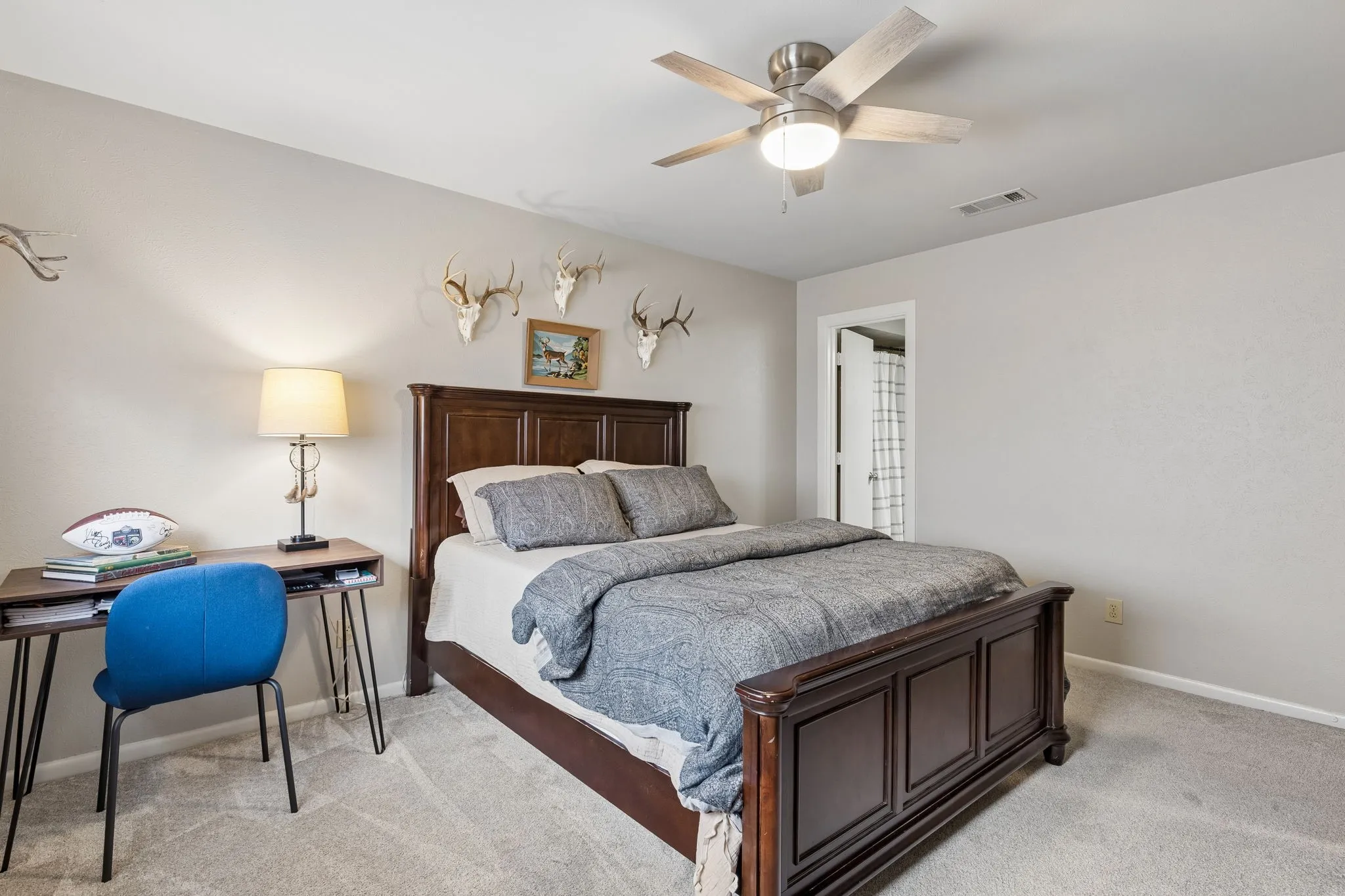 Carpeted bedroom featuring a dark wood bed frame, a ceiling fan with integrated lighting, and neutral wall tones