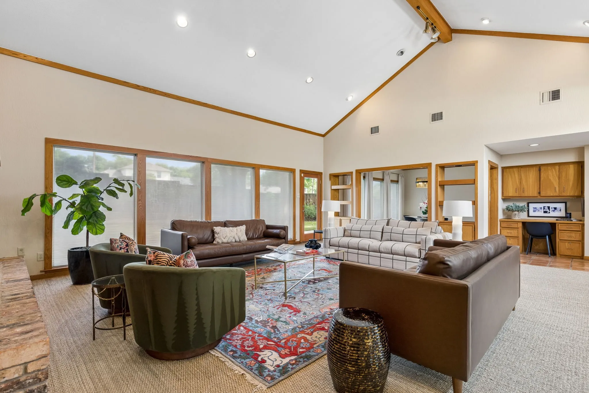 Spacious living area featuring a vaulted ceiling with exposed wood beams, recessed lighting, and expansive windows