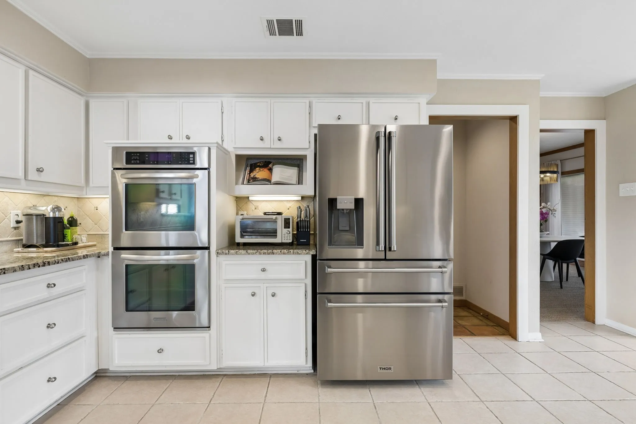 Kitchen featuring white cabinetry, granite countertops, stainless steel double wall ovens, and a stainless steel French door refrigerator