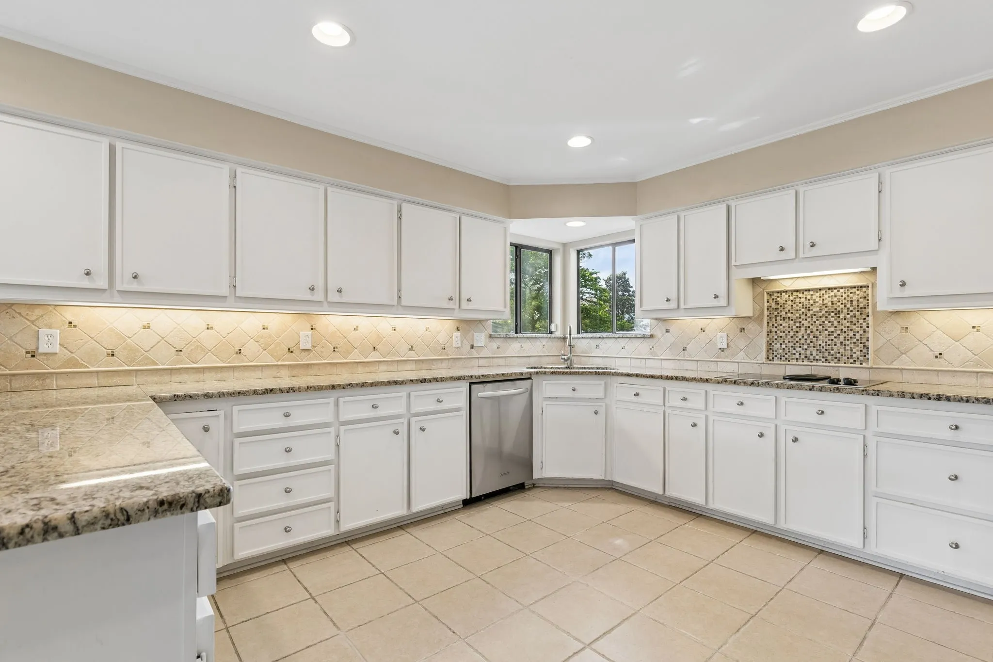 Spacious kitchen featuring white cabinetry, granite countertops, a tiled backsplash, stainless steel appliances, and recessed lighting