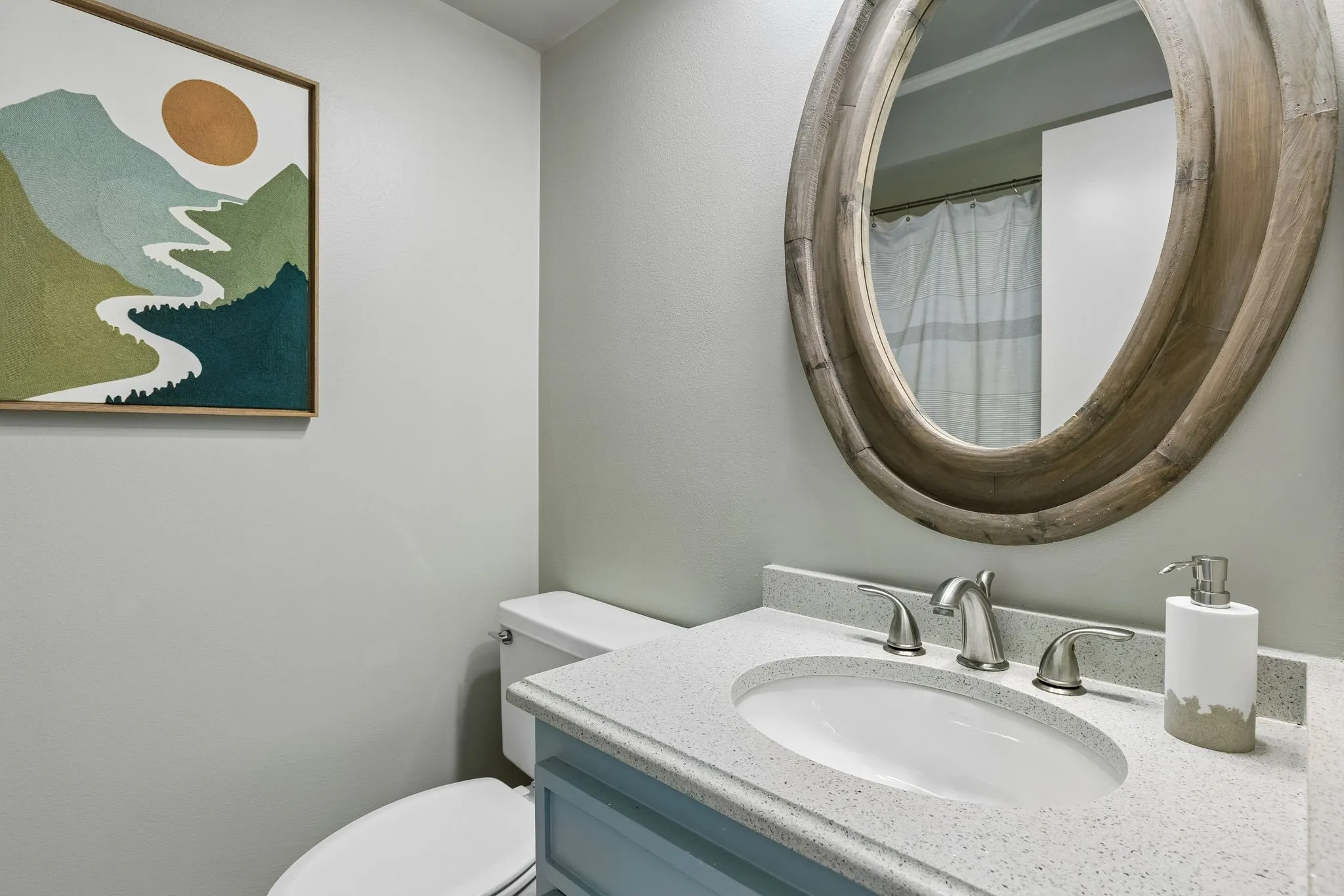 Powder room with a light blue vanity, integrated sink, and brushed nickel faucet