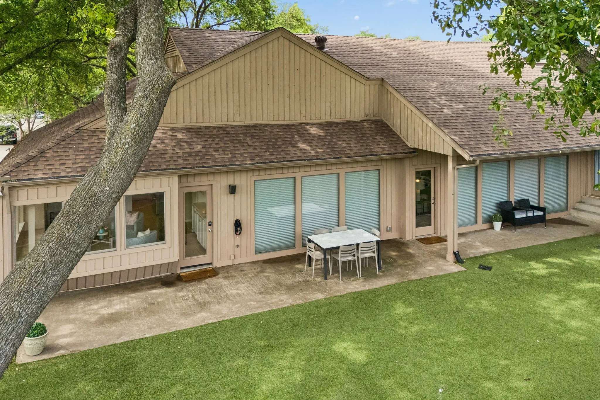 Expansive rear exterior featuring a concrete patio, abundant window space, and a combination of board and batten and horizontal siding