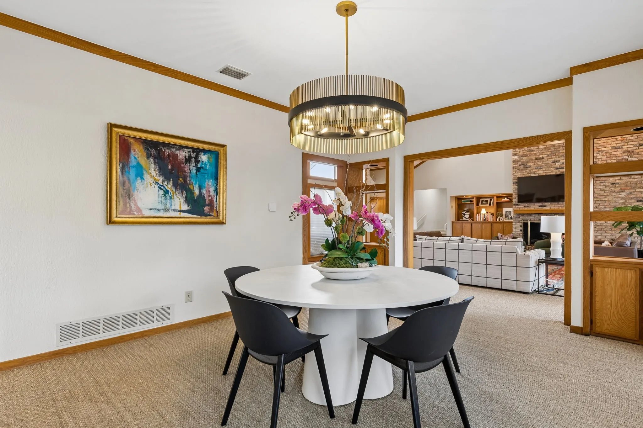 Dining area featuring a contemporary round chandelier, light-toned carpeting, and wood-trimmed doorways