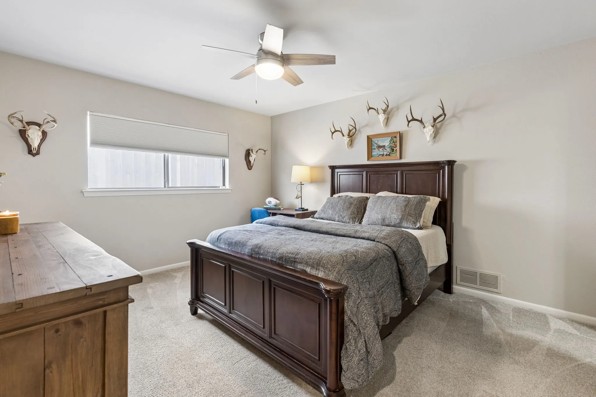 Spacious room featuring neutral carpeting, light-toned wall paint, and a ceiling fan with integrated lighting