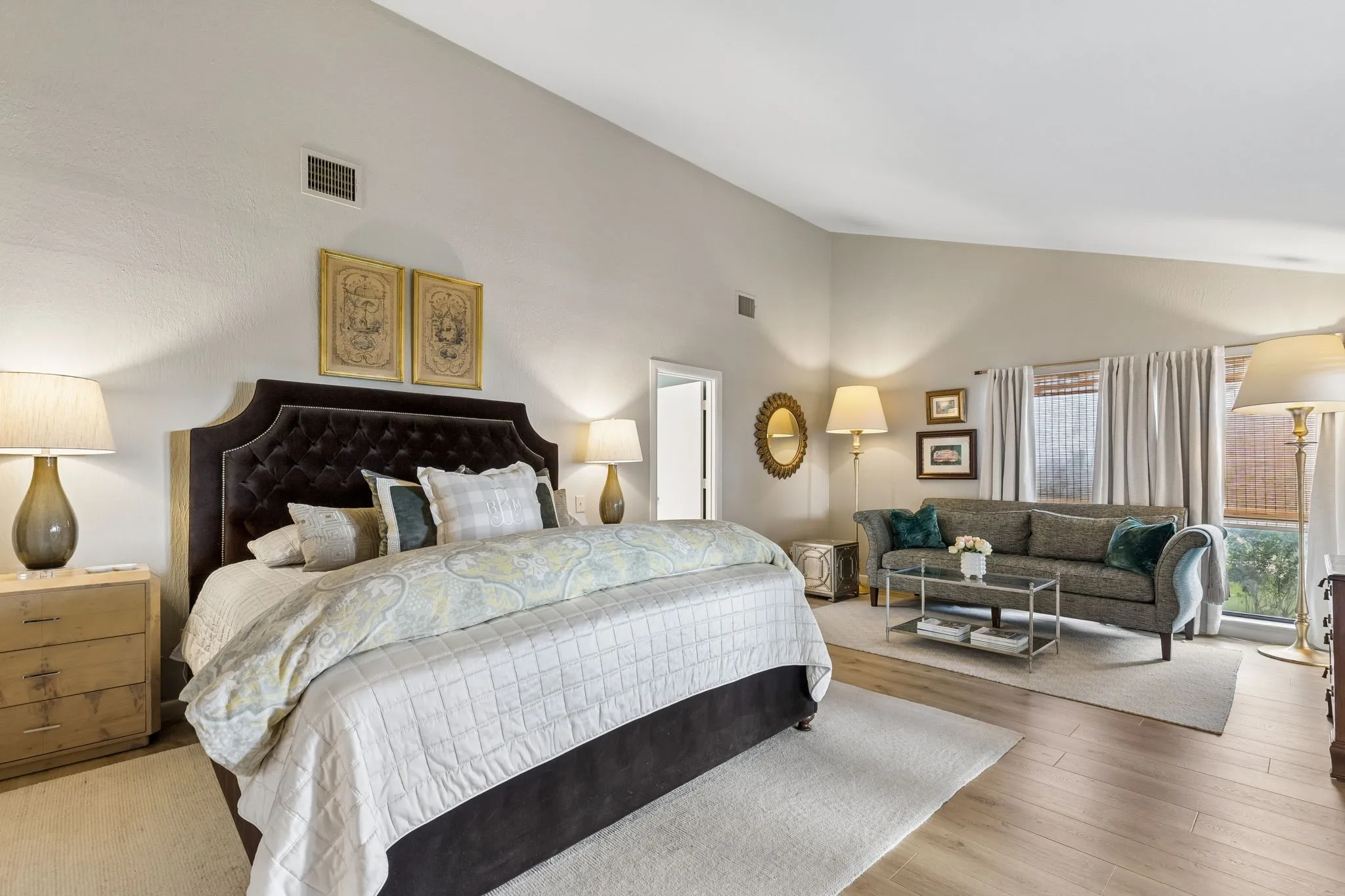 Spacious room featuring vaulted ceilings, wood-finish flooring, and expansive windows