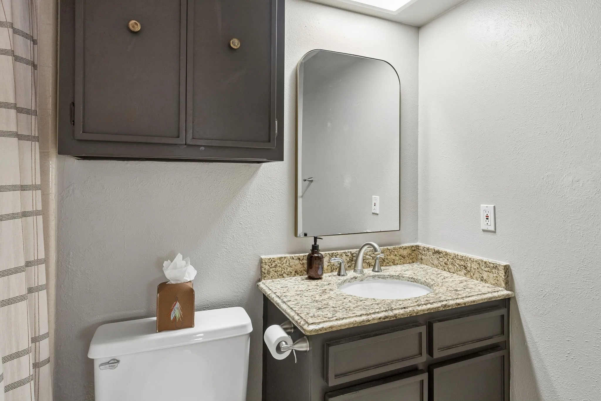 Bathroom vanity with a granite countertop, undermount sink, and brushed nickel faucet