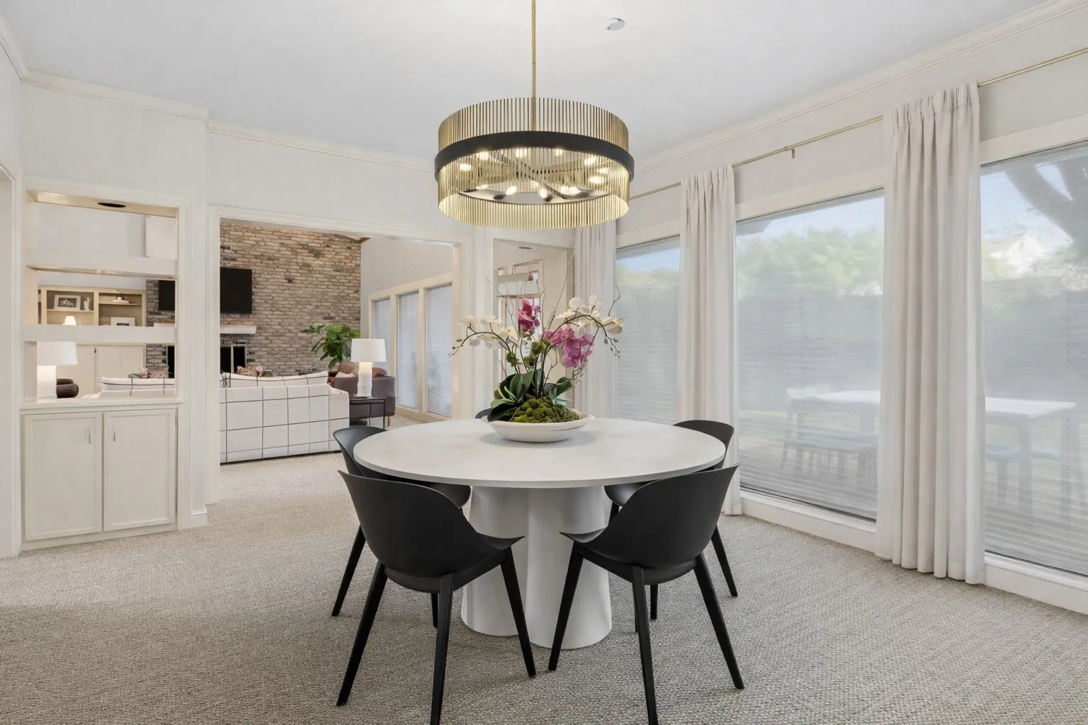 Dining area featuring a contemporary chandelier, large windows with privacy blinds, and a built-in display cabinet with lower storage
