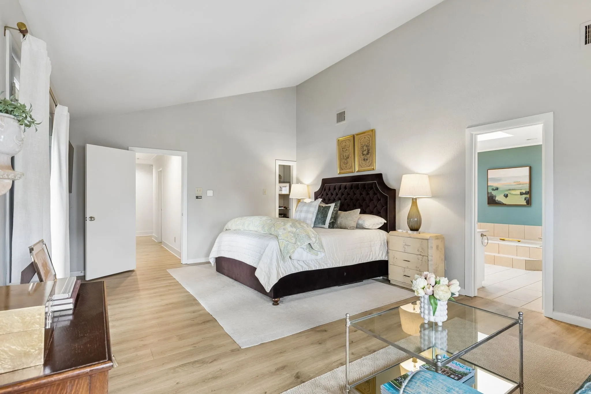 Spacious room featuring vaulted ceilings, wood-finish flooring, and a neutral color palette