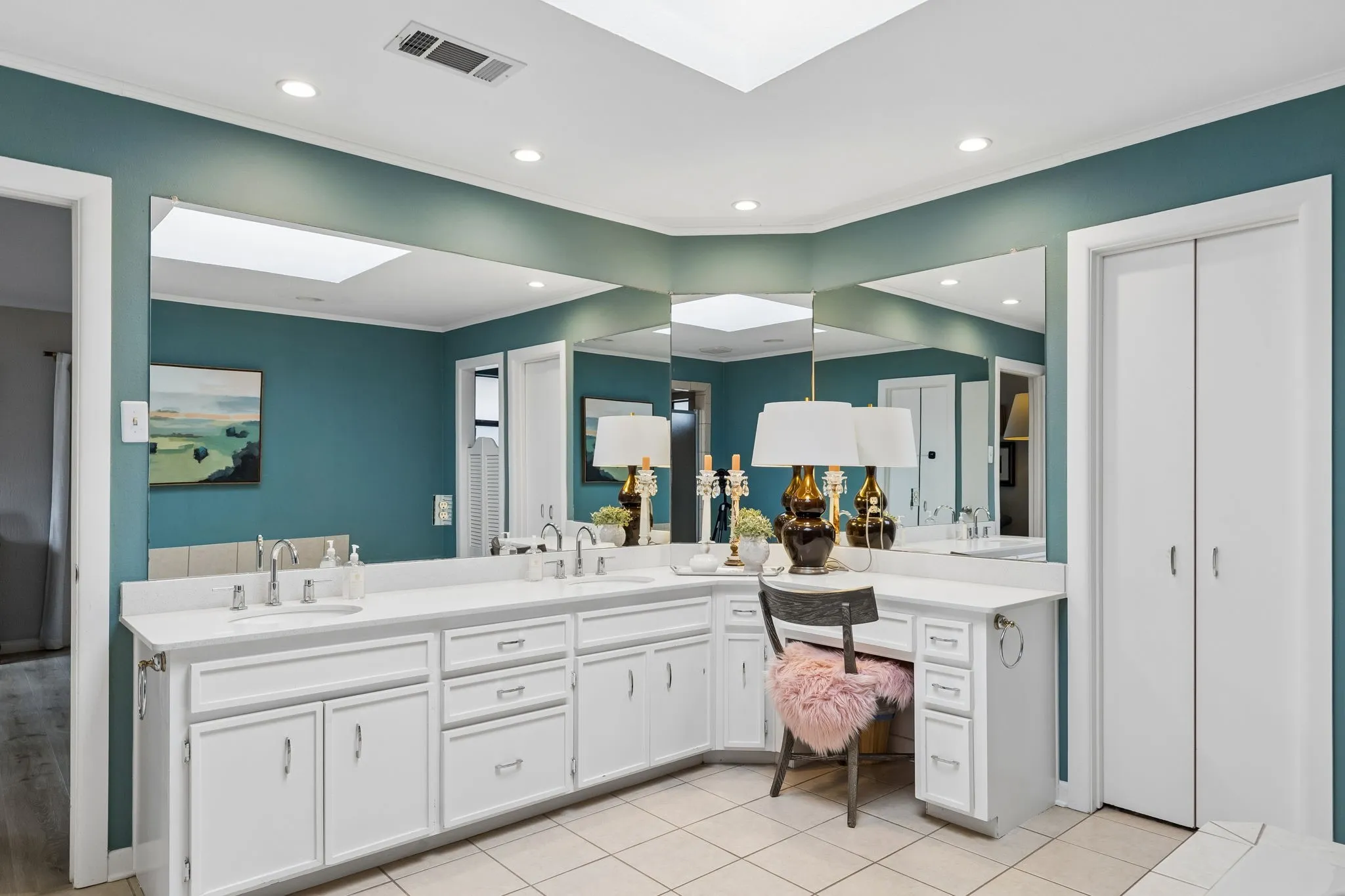 Bathroom featuring a skylight, recessed lighting, and a dual vanity with white cabinetry