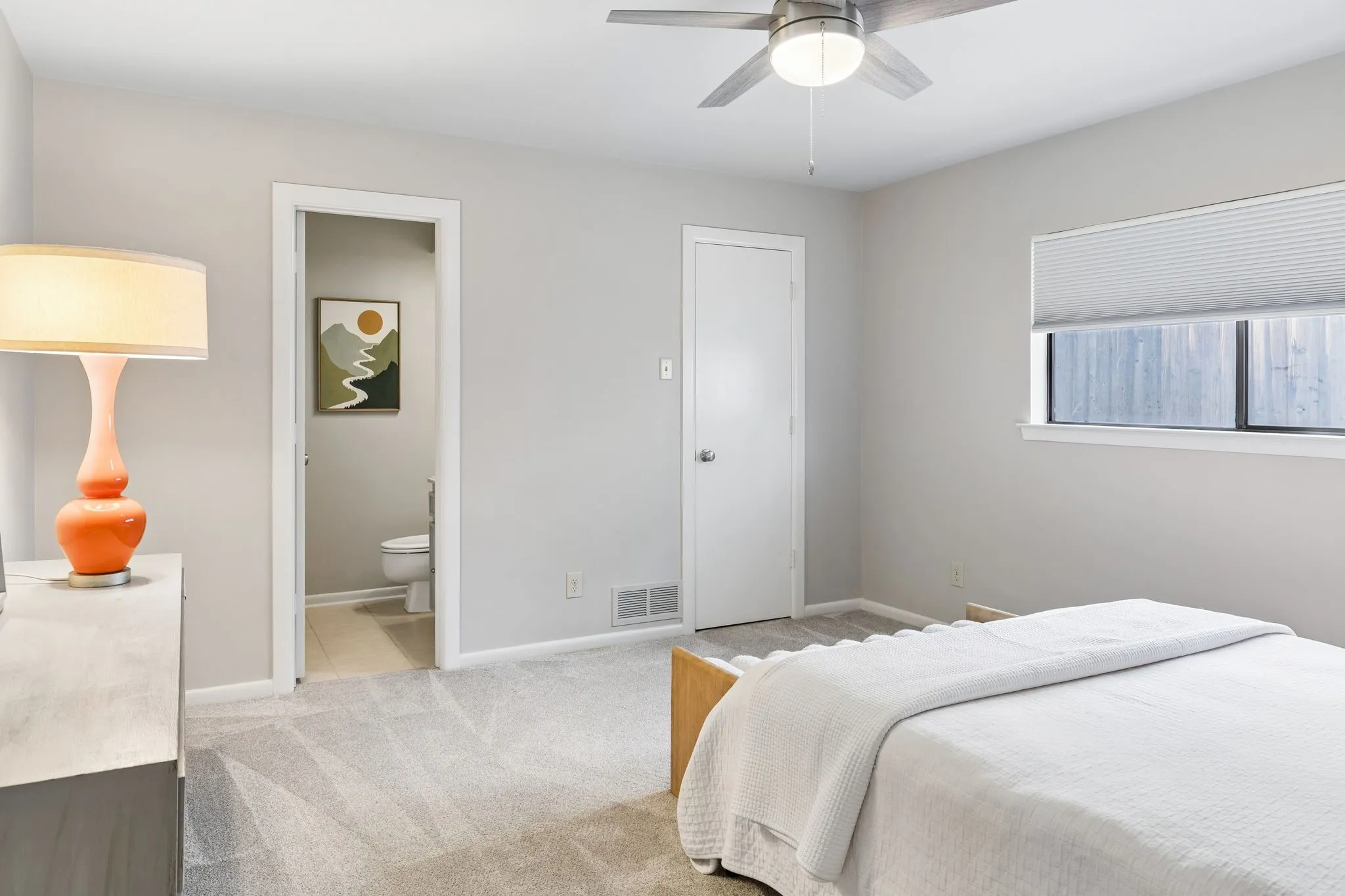 Bedroom with light gray walls, gray patterned carpet, and a ceiling fan with integrated lighting
