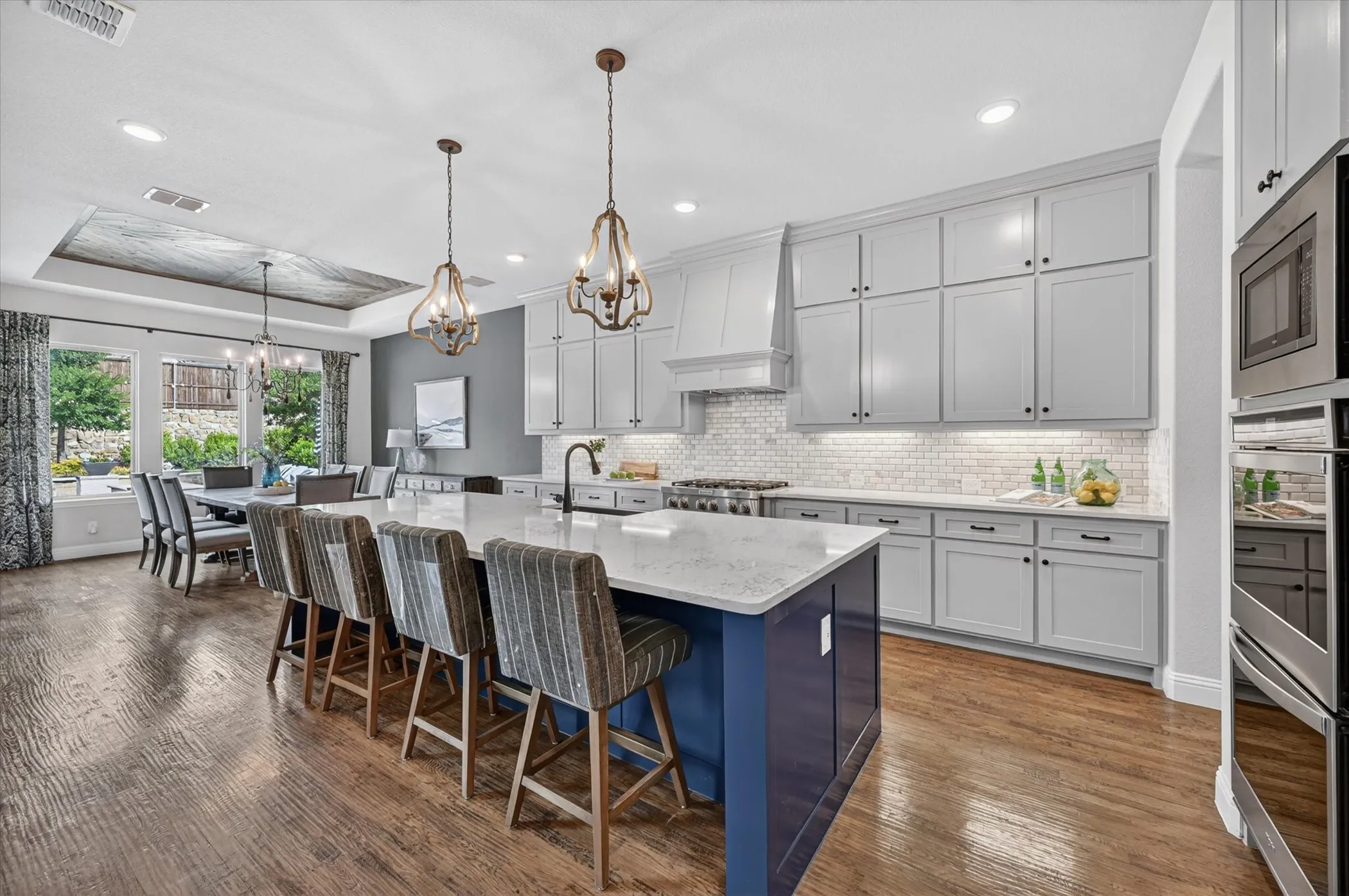 The chef’s kitchen is equally impressive, offering quartz countertops, a marble backsplash, a six-burner gas rangetop, double ovens, and a large island with breakfast bar seating.
