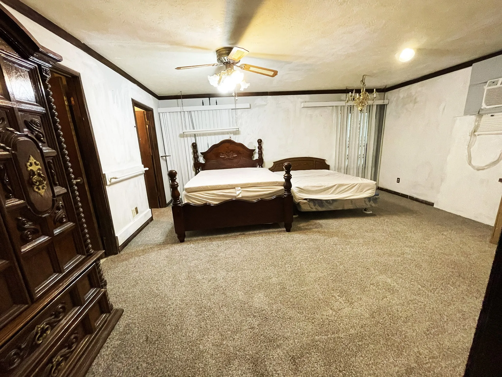 Spacious room featuring neutral carpeting, a ceiling fan with integrated lighting, and a window unit air conditioner