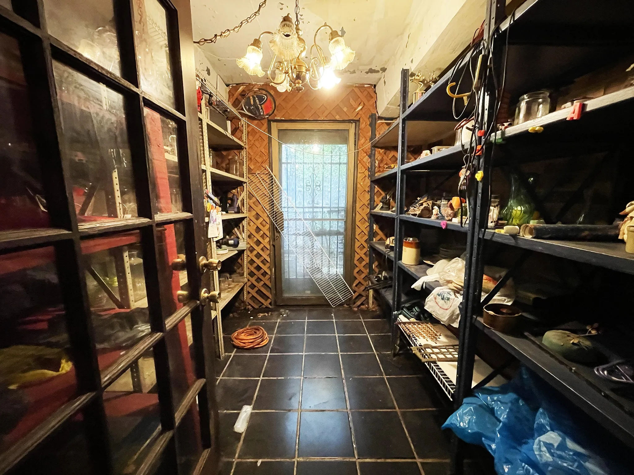 Room featuring a chandelier-style ceiling light, dark square floor tiles, and a rear door with security bars