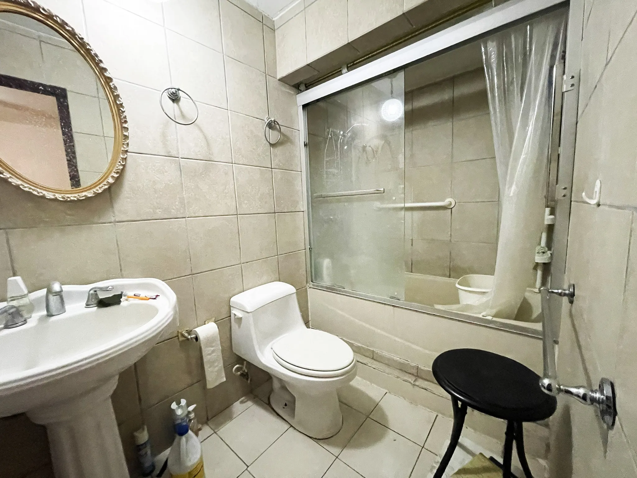 Bathroom featuring a pedestal sink, a toilet, and a combination tub/shower with sliding glass doors and grab bars