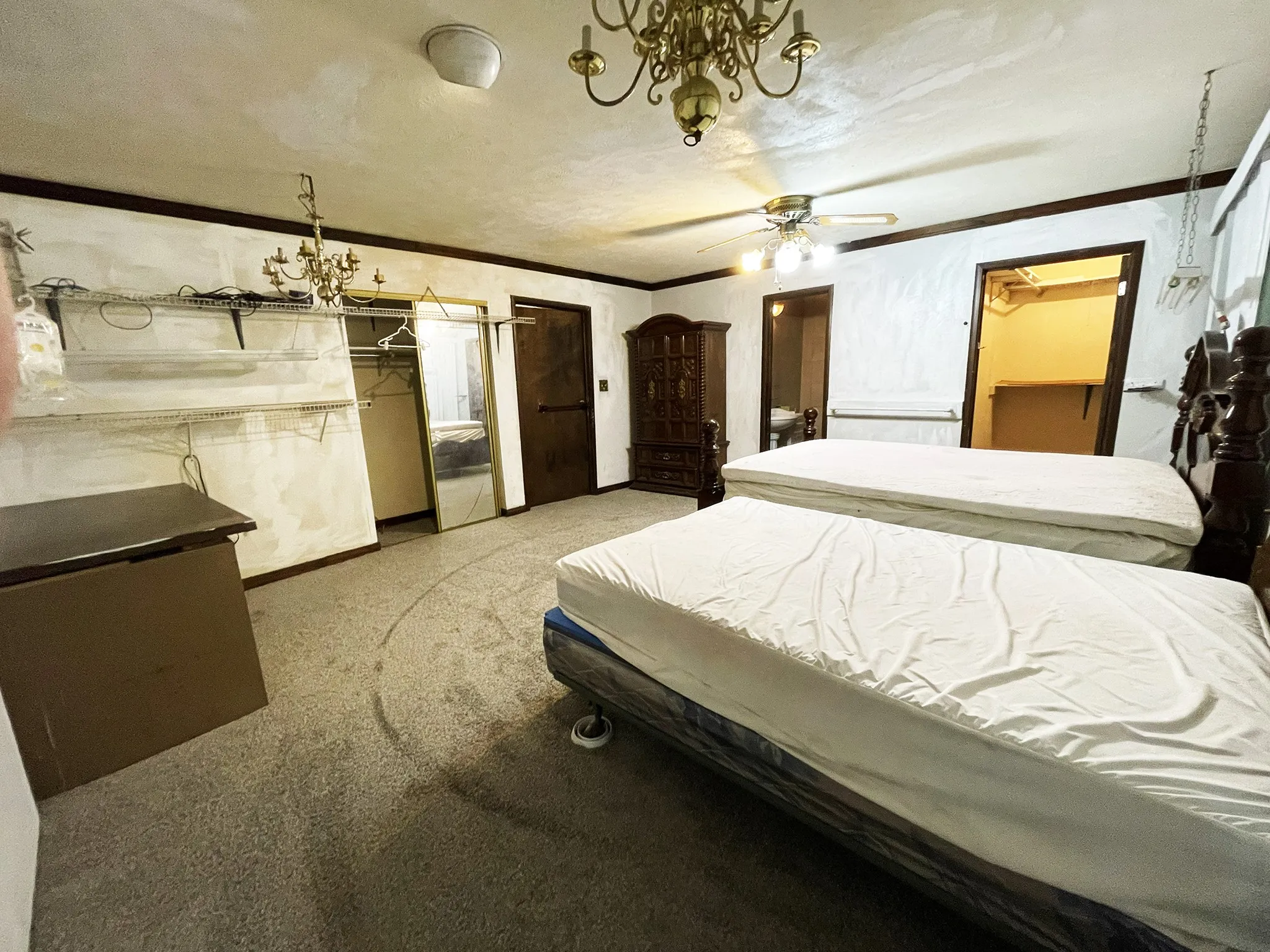 Carpeted room featuring a ceiling fan, two chandeliers, and dark wood trim