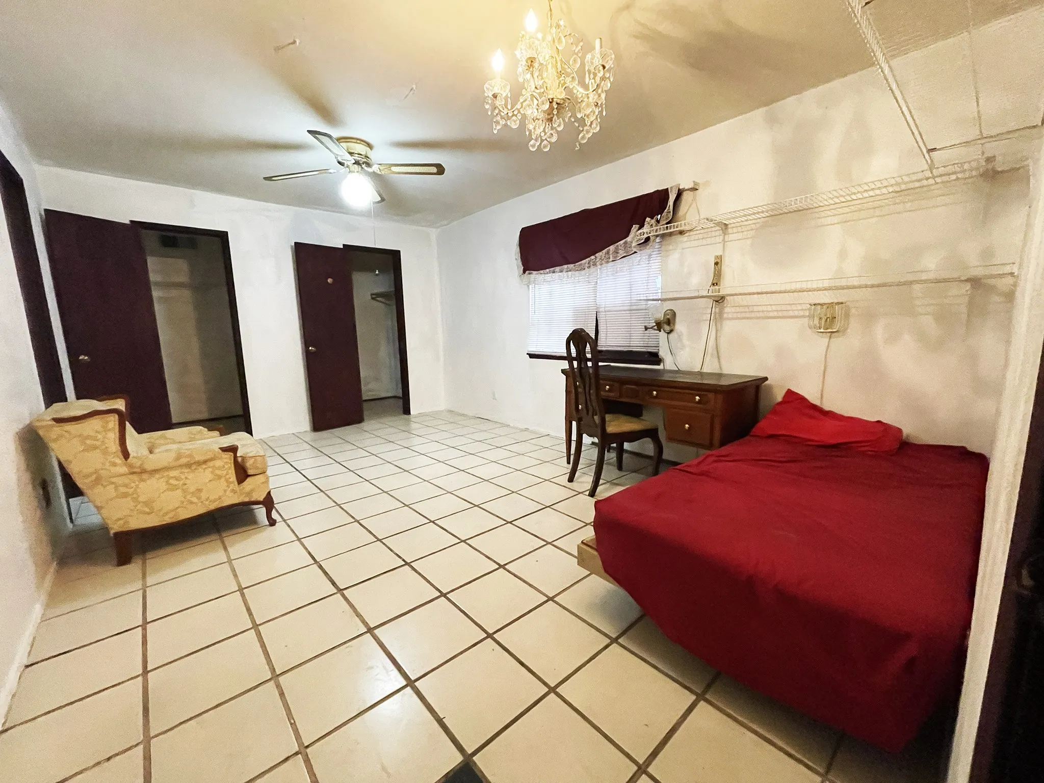 Spacious room featuring tile flooring, a ceiling fan, and a chandelier light fixture