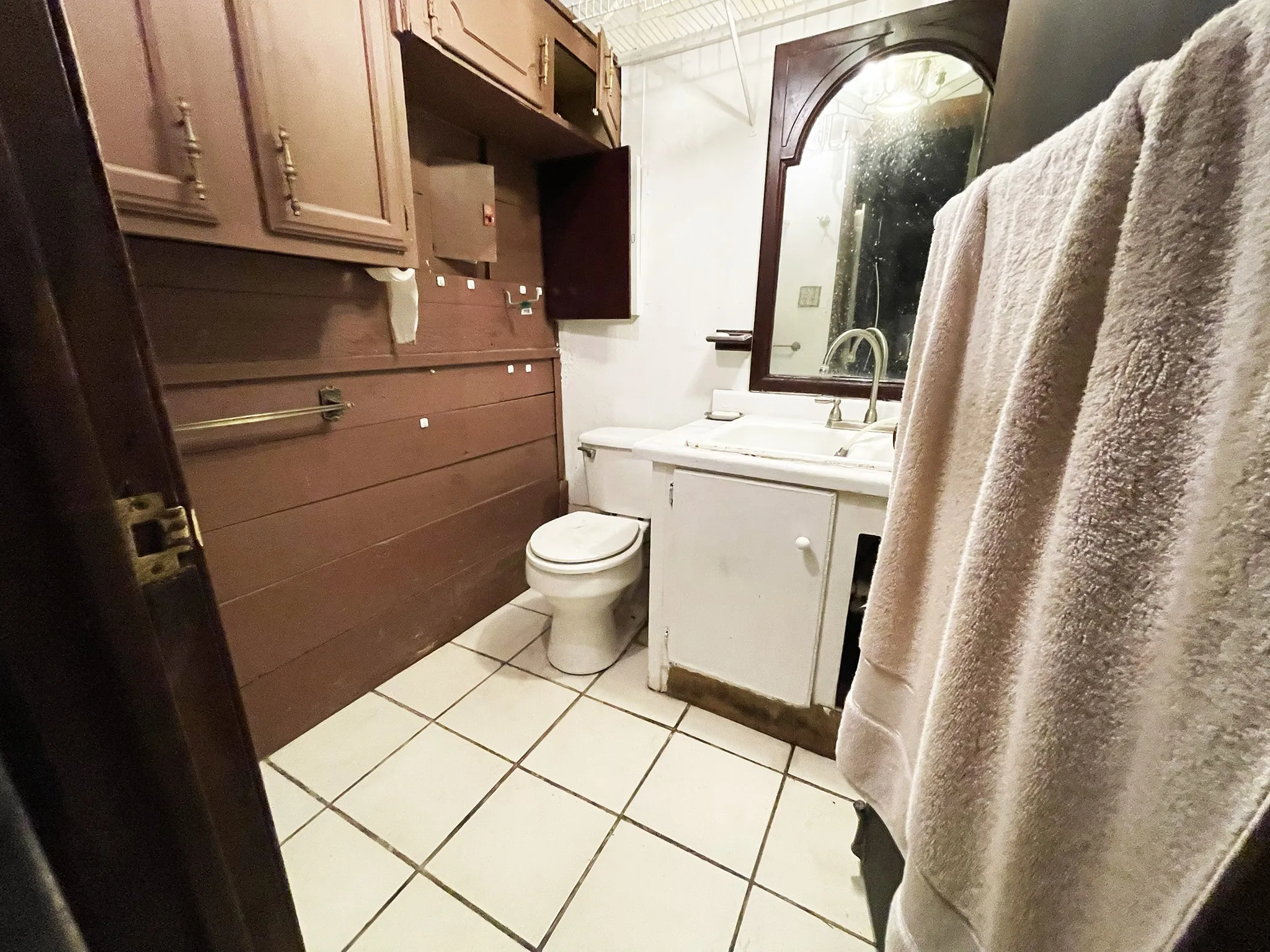 Bathroom featuring white square tile flooring, a white toilet, and a white vanity with an integrated sink and chrome faucet