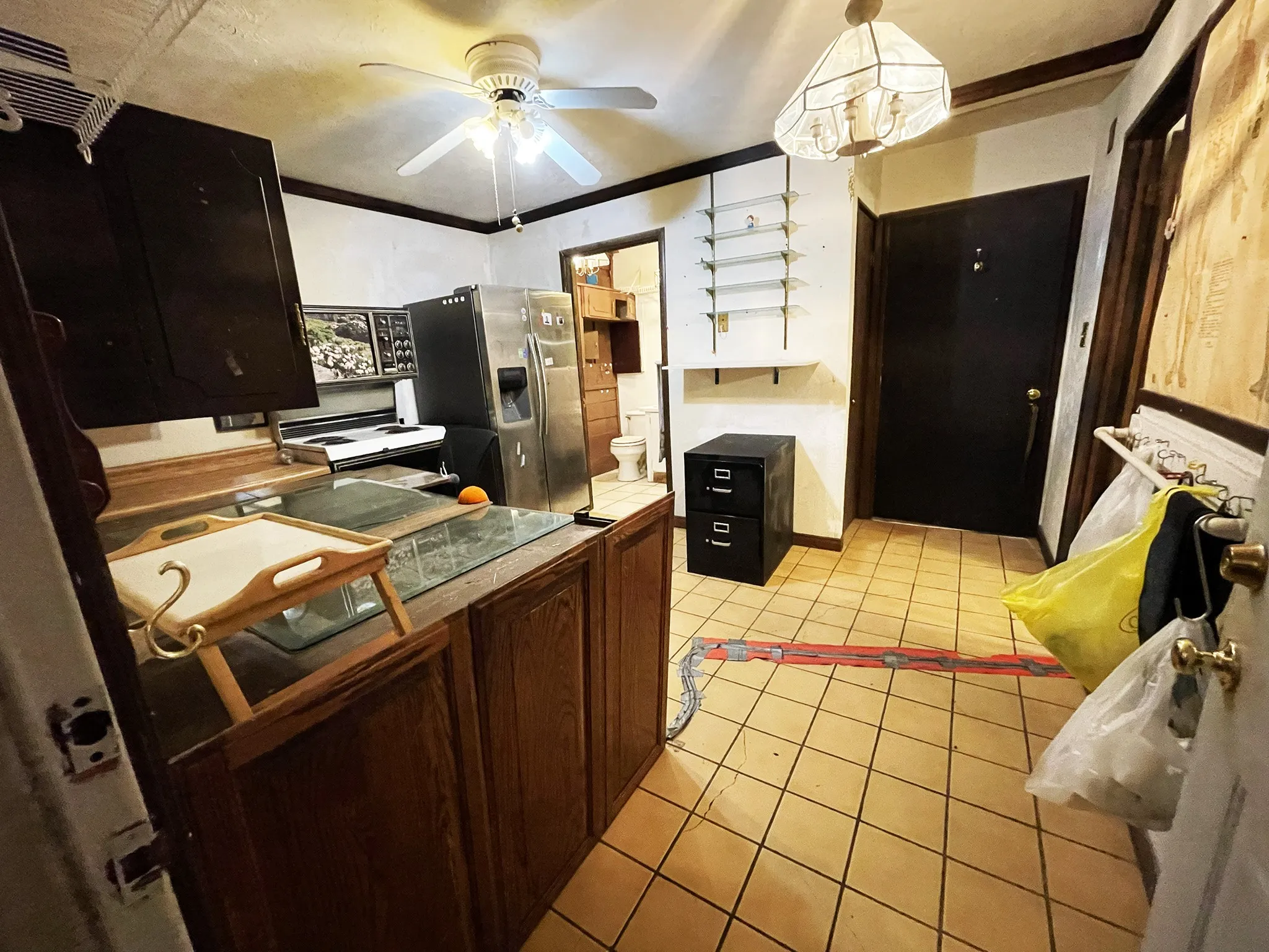 Kitchen area featuring tile flooring, wooden cabinetry, built-in shelving, a ceiling fan, and a light fixture