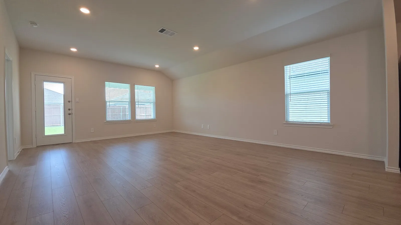 Spacious open-concept room featuring light wood-finish flooring and neutral wall tones
