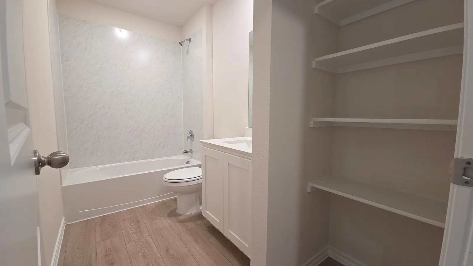 Full bathroom featuring a white tub, shower with a textured surround, single vanity with white cabinetry, and wood-finish flooring