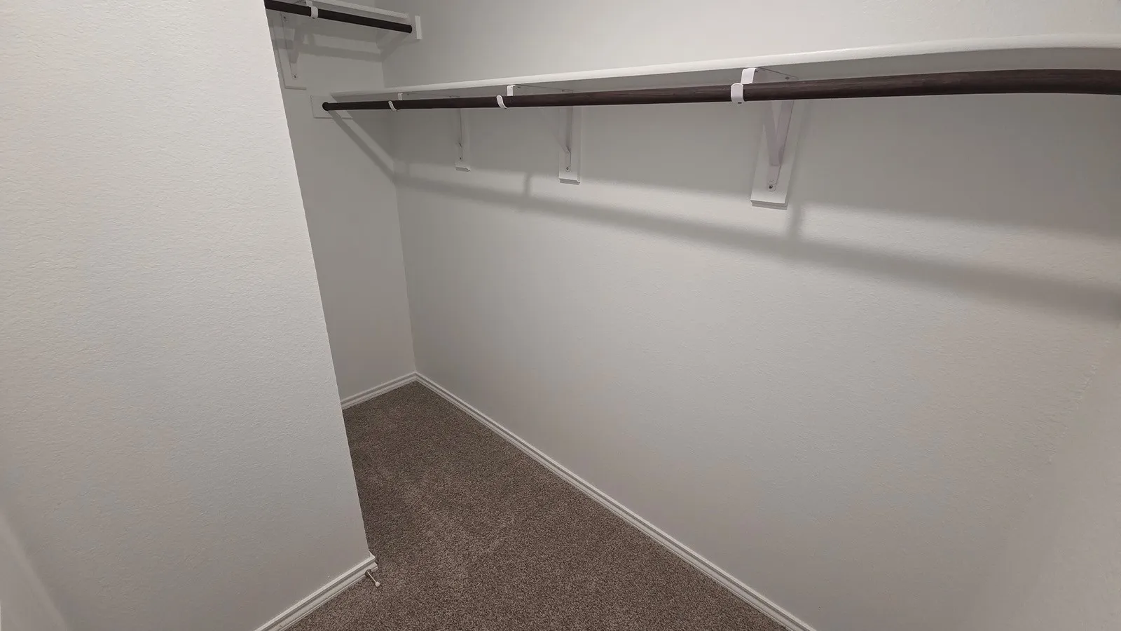 Walk-in closet with carpet flooring, white walls, and two levels of shelving and hanging rods