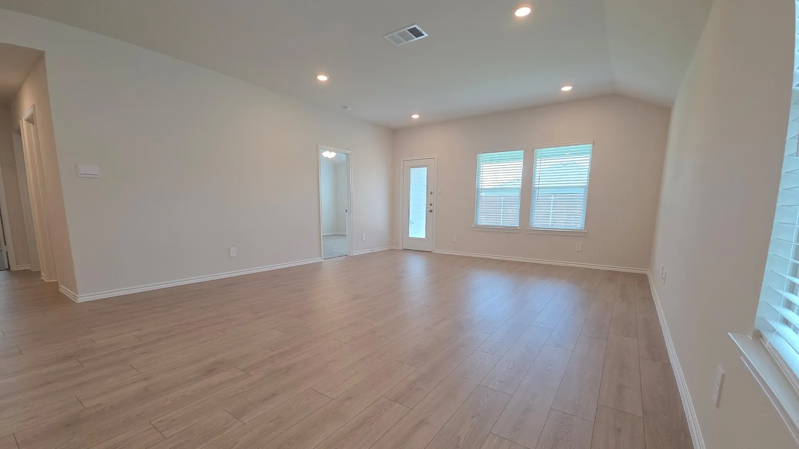 Spacious interior featuring wood-finish flooring, recessed lighting, and a vaulted ceiling