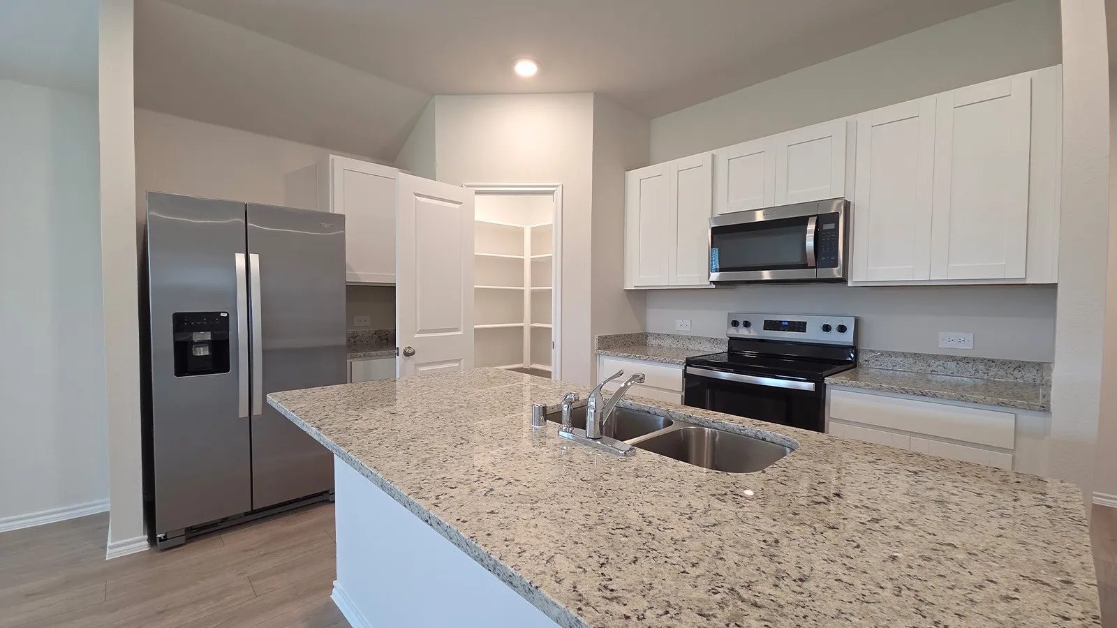 Kitchen island with a double basin sink and a chrome faucet set against granite-finish countertops
