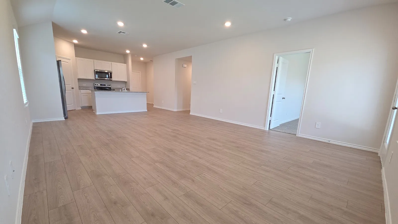 Open-concept living area featuring wood-finish flooring, recessed lighting, and a neutral color palette