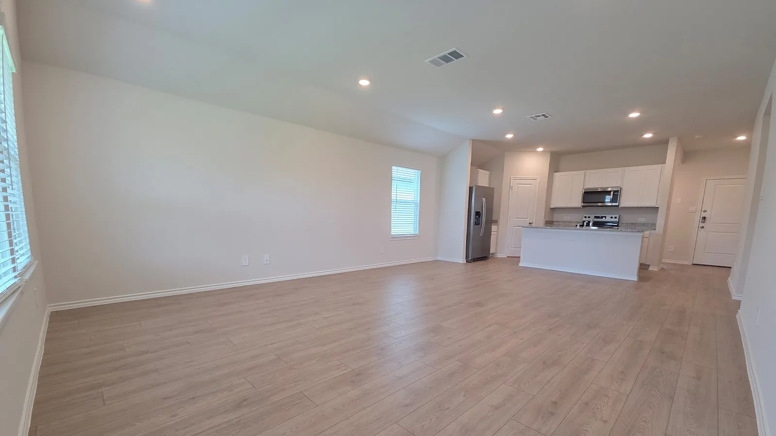 Open-concept living space featuring wood-finish flooring, recessed lighting, and a window with blinds