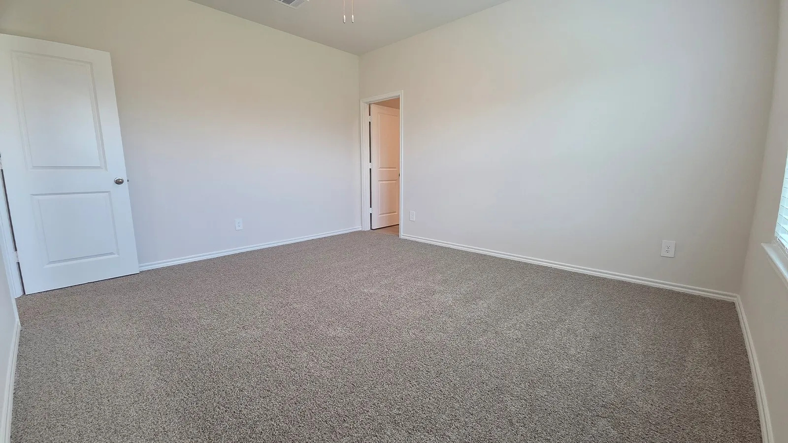 Spacious room featuring neutral carpeting, white walls, and white trim