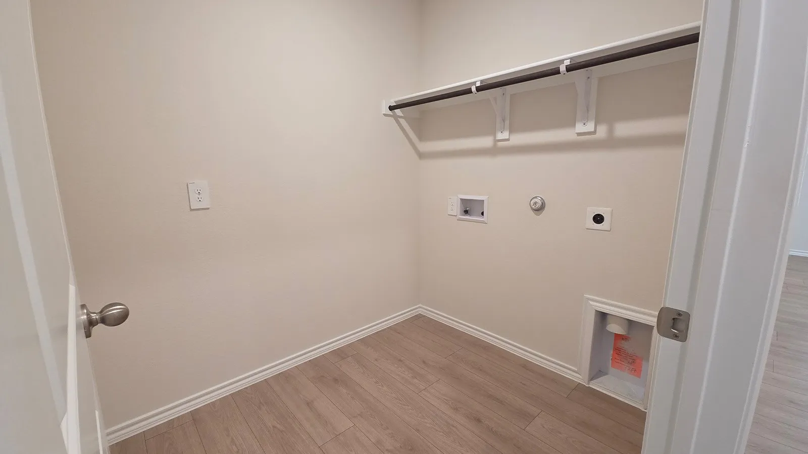 Utility room with wood-finish flooring, white baseboards, and neutral wall tones