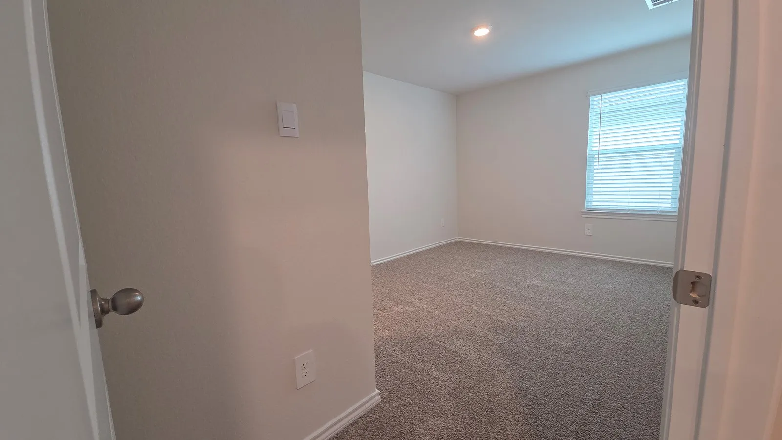 Carpeted interior room featuring a single window with blinds, recessed lighting, and neutral wall paint