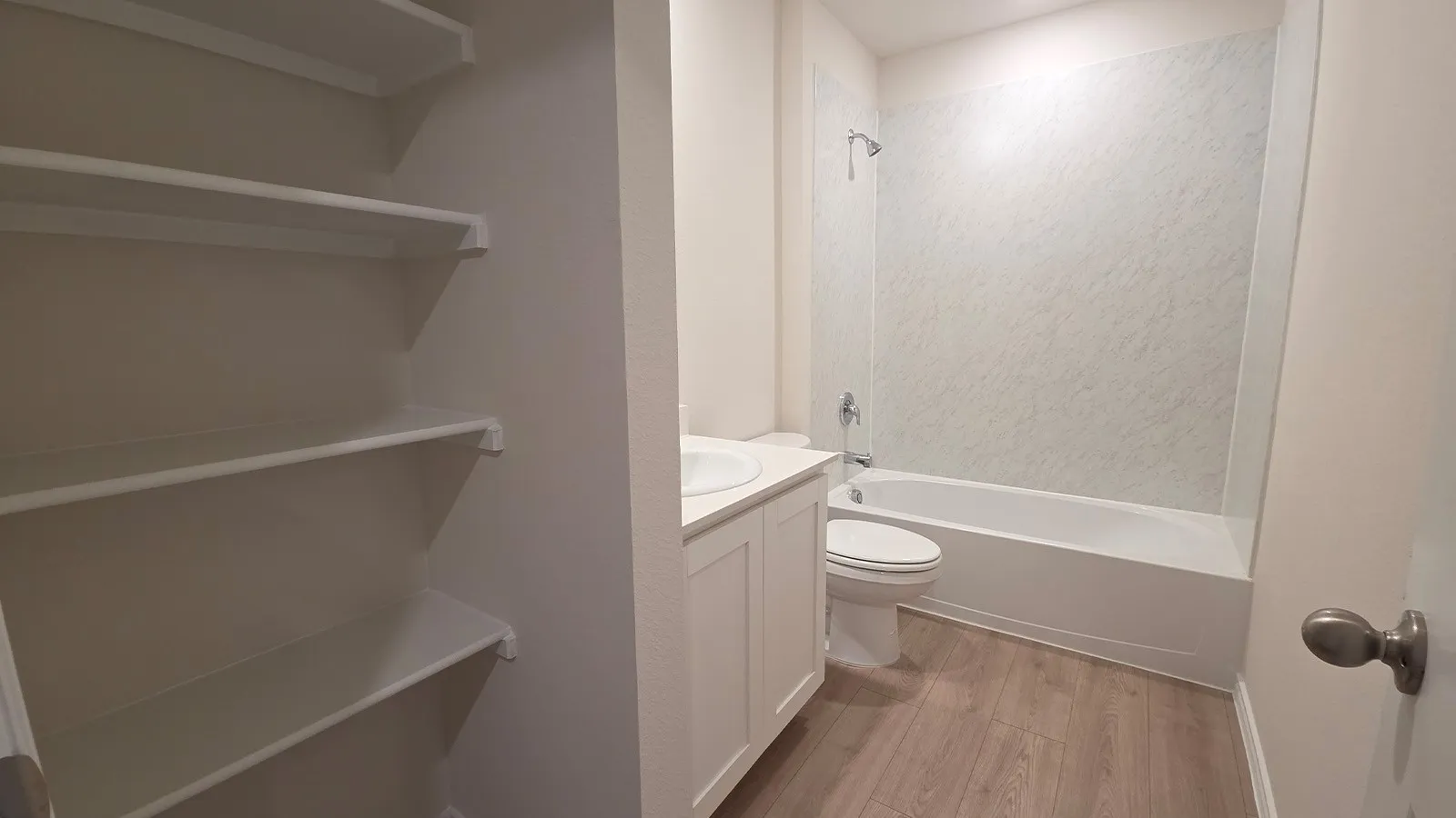 Bathroom featuring a full tub/shower combination with textured wall surround, white vanity with integrated sink, chrome fixtures, and wood-finish flooring