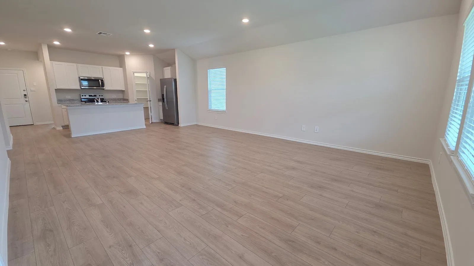 Expansive open-concept living space with light wood-finish flooring
