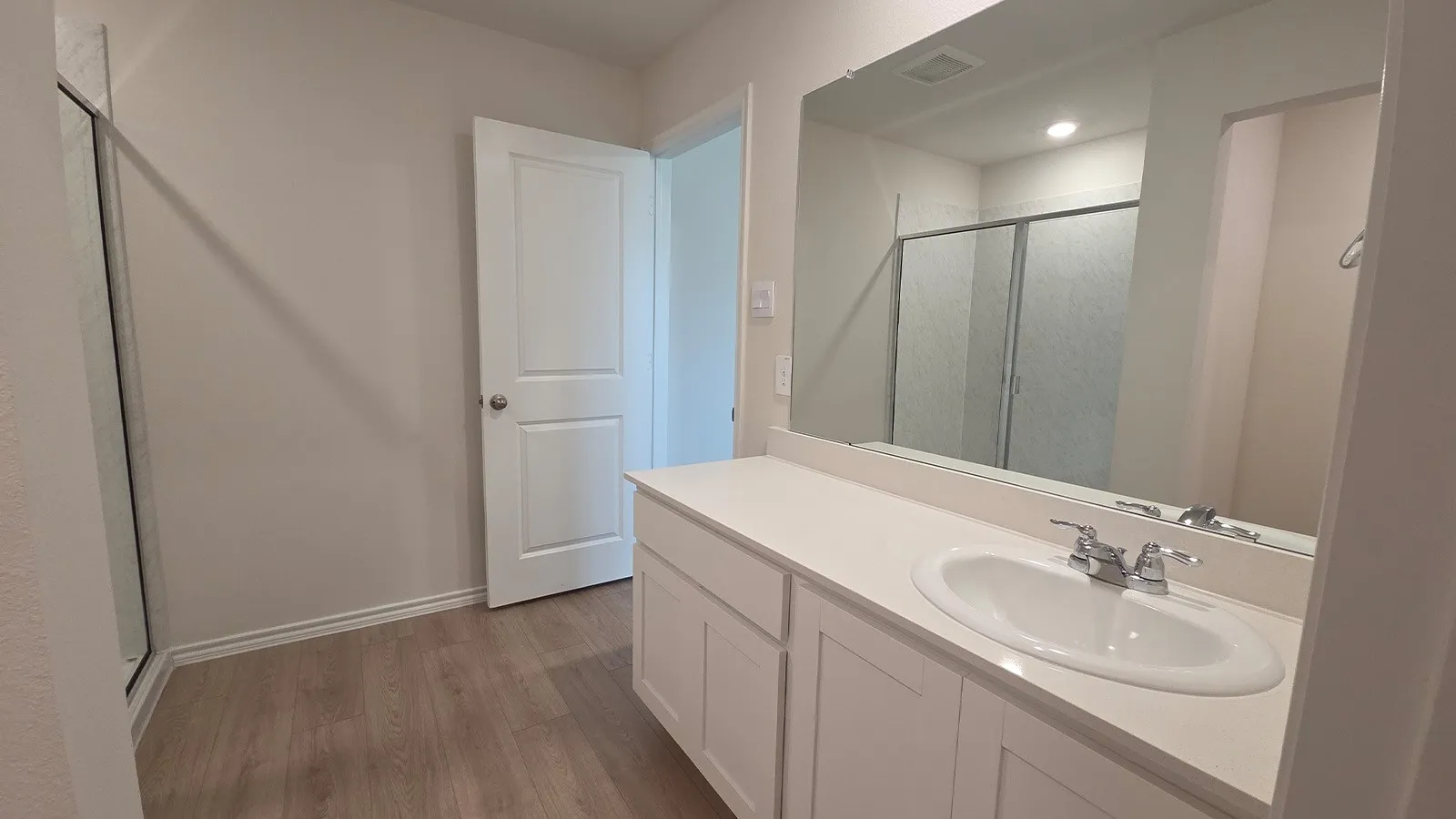 Bathroom vanity featuring an integrated oval sink, chrome faucet, and expansive wall-mounted mirror