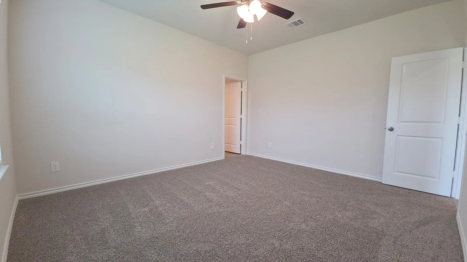 Spacious room featuring neutral carpeting, light-toned walls, and a ceiling fan with integrated lighting