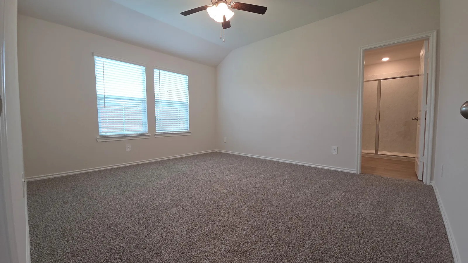 Spacious room with vaulted ceiling and neutral carpeting