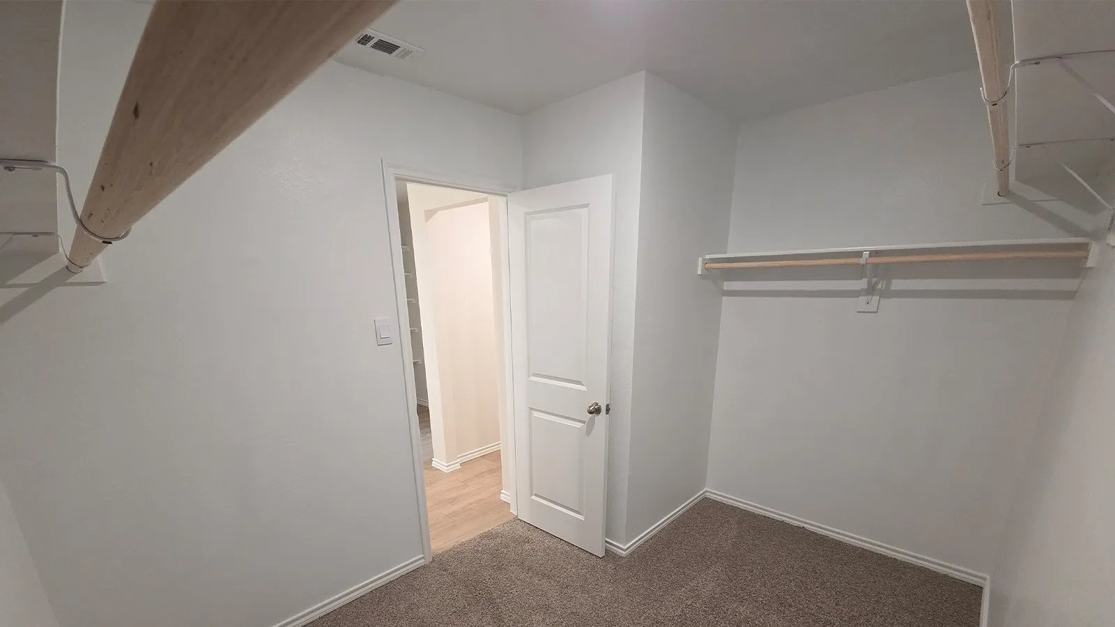 Walk-in closet featuring carpet flooring, crisp white walls, and built-in shelving with hanging rods