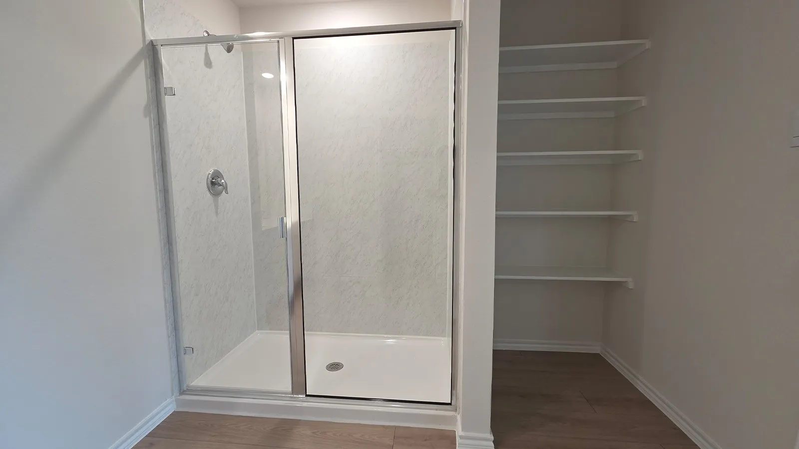 Walk-in shower with clear glass enclosure and chrome fixtures